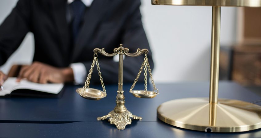 Elegant legal office with a close-up of golden scales of justice on a sleek dark desk.